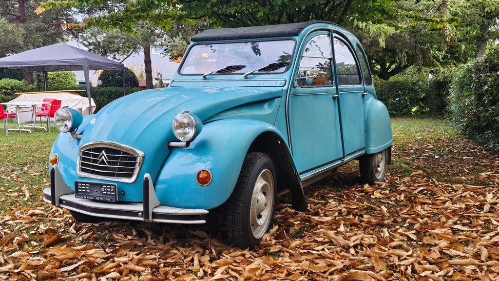 Citroën 2CV bleue à capote noire, stationnée sur un tapis de feuilles mortes lors de la brocante de Meyrin.
